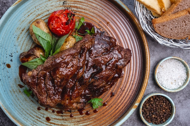 Close-up de bife cozido com molho, batata bebê e tomate