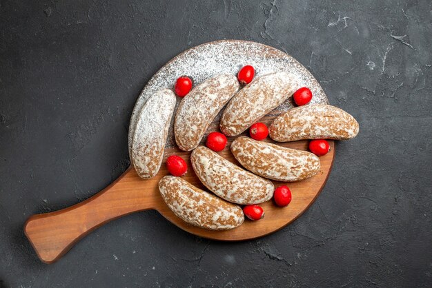 Close-up de biscoitos de banana com frutas em uma tábua de corte marrom no escuro