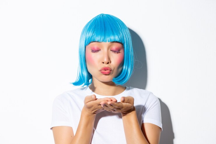 Foto grátis close-up de boba atraente mulher asiática com maquiagem glam e peruca azul, soprando ar beijo para a câmera, vestindo fantasia de halloween.