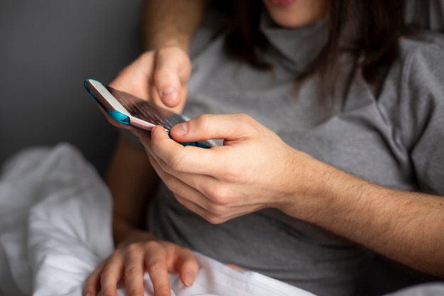 Close-up de casal abraçando enquanto olha para o smartphone