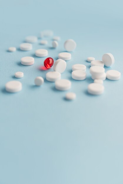 Close-up de comprimidos brancos com medicamento cápsula vermelha