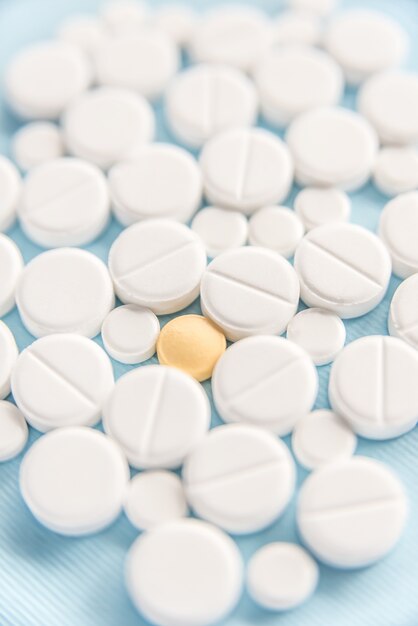 Close-up de comprimidos brancos com uma pílula amarela