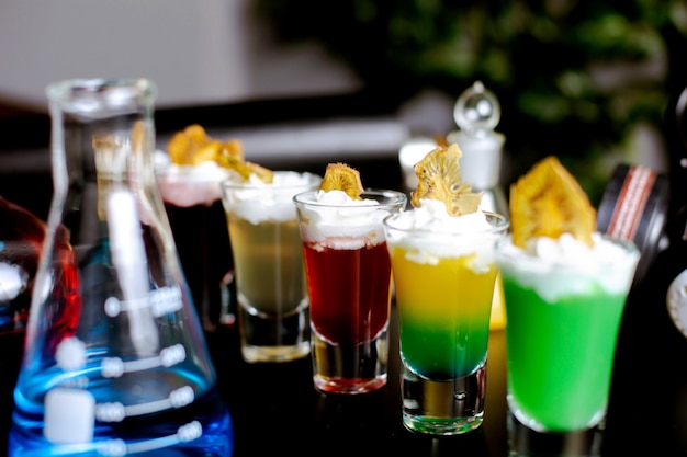 Close-up de copos de shot com cocktails guarnecidos com chantilly e frutas secas