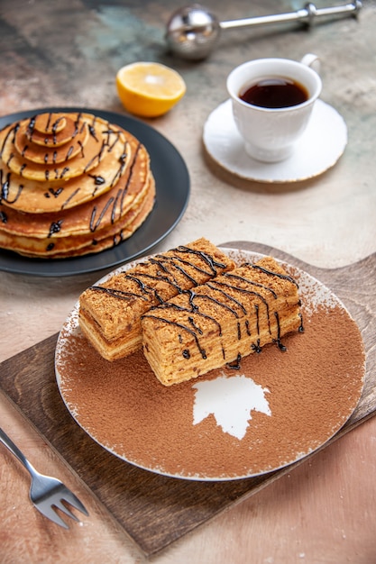 Close-up de deliciosas sobremesas e uma xícara de chá de limão e canela na mesa colorida