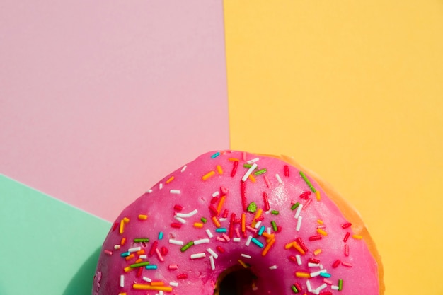 Foto grátis close-up de donut com polvilha contra amarelo; rosa; e pano de fundo verde menta