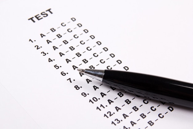 Close up de folha de papel de pontuação de teste com respostas e caneta de metal