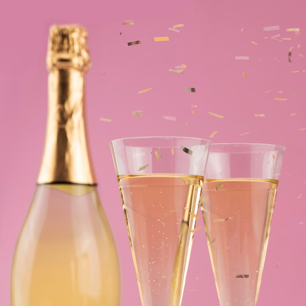 Close-up de garrafa de champanhe com copos e confetes