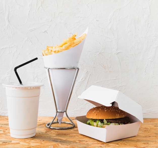 Foto grátis close-up de hambúrguer; batatas fritas e copo de eliminação na mesa de madeira