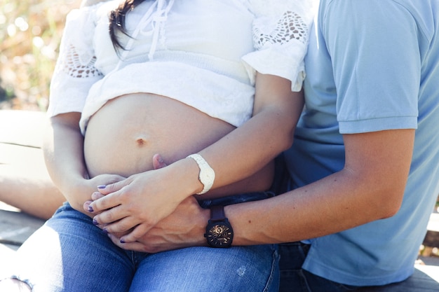 Close-up de hnads de casal sobre a barriga grávida