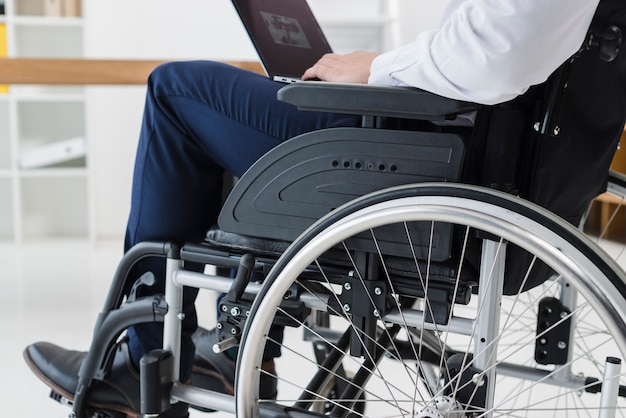 Close-up, de, homem negócios, sentando, ligado, cadeira rodas, usando computador portátil