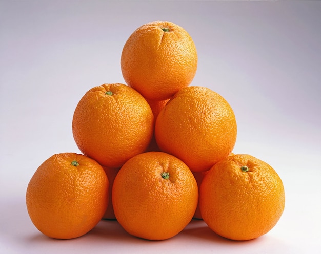 Close up de laranjas em cima da outra em uma superfície branca - ótimo para um plano de fundo