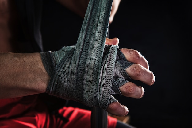 Close-up de mão com bandagem de homem musculoso treinando kickboxing no preto