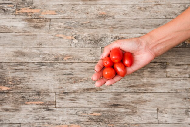 Close-up, de, mão mulher, segurando, vermelho, tomates cereja, ligado, tábua madeira