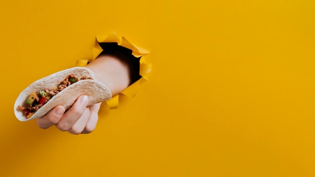 Foto grátis close-up de mão segurando um taco com cópia-espaço