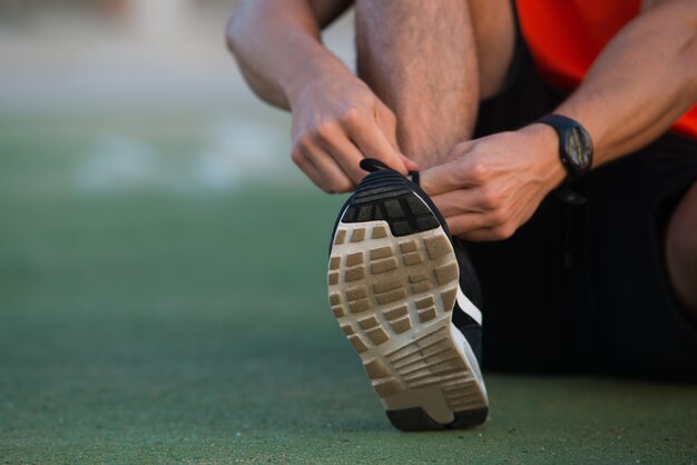 Close-up de mãos do sexo masculino amarrando sapatos esportivos