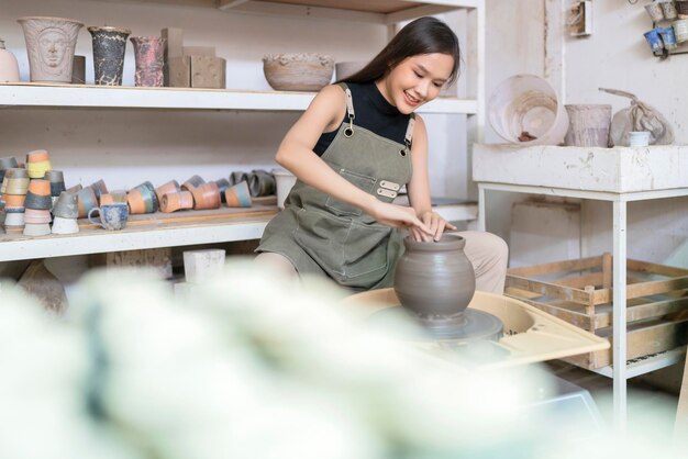 Close-up de mãos femininas trabalhando em oleiros wheelasian escultura feminina mulher moldando molde pequeno vaso tigela argila na roda de oleiro em casa estúdio oficina arte e criação conceito de hobby