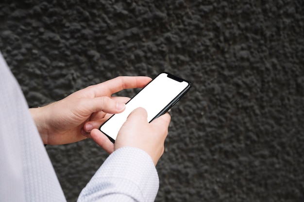 Foto grátis close-up de mãos masculinas usando smartphone com tela em branco