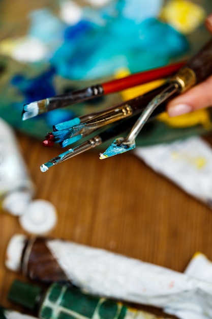 Foto grátis close-up de mãos segurando pincéis e faca de paleta