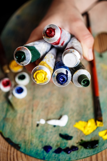 Foto grátis close-up de mãos segurando tintas a óleo, parede de paleta