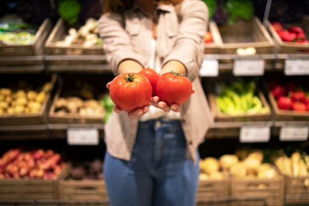 Close-up de mãos segurando tomates vegetais no supermercado