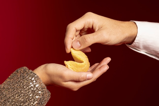 Foto grátis close-up de mãos segurando um biscoito da sorte para o ano novo chinês