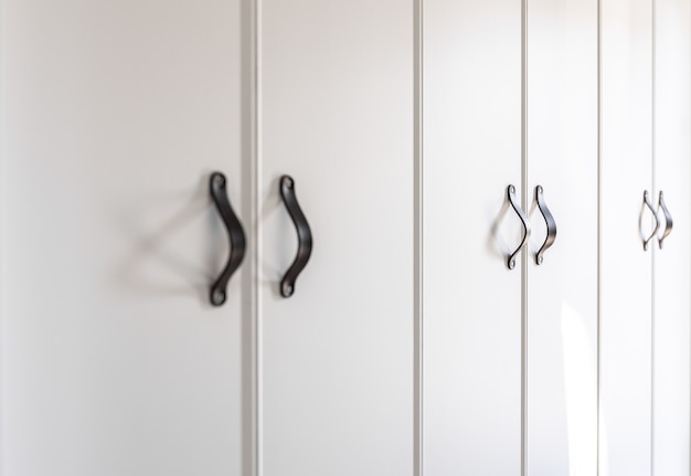 Close-up de móveis brancos minimalistas com alças pretas, detalhes de armário de cozinha