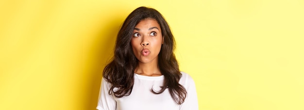 Close-up de mulher afro-americana impressionada em camisa branca dizendo wow olhando para o canto superior esquerdo um