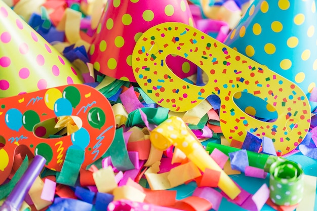 Close-up de papel mascaras perto de chapéus de festa