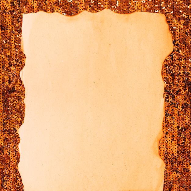 Foto grátis close-up de papel queimado contra têxteis de lantejoulas