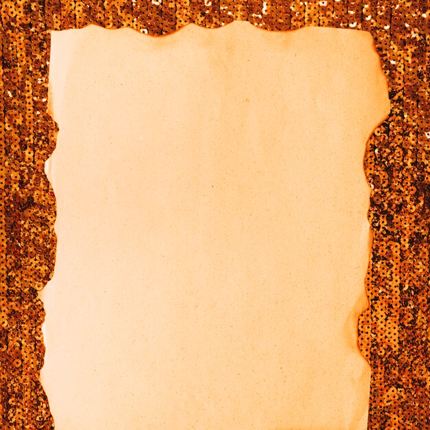 Close-up de papel queimado contra têxteis de lantejoulas