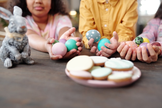 Close-up de prato com biscoitos caseiros com um grupo de crianças sentadas ao fundo segurando ovos de páscoa
