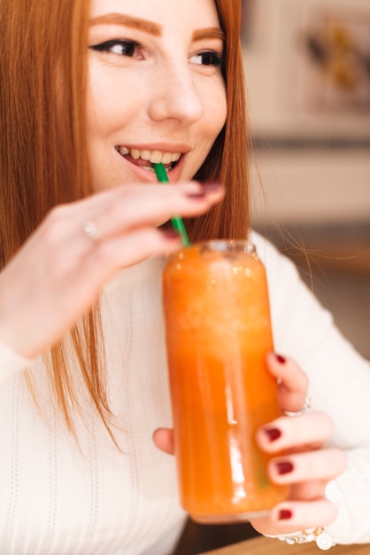 Foto grátis close-up, de, sorrindo, mulher jovem, bebendo, a, suco laranja, com, palha