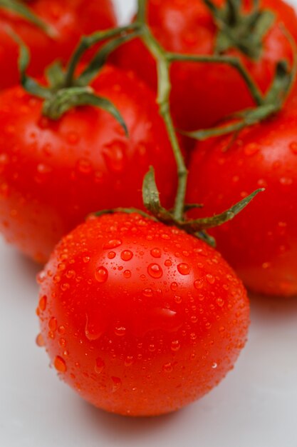 Close-up de tomates maduros molhados em uma superfície branca