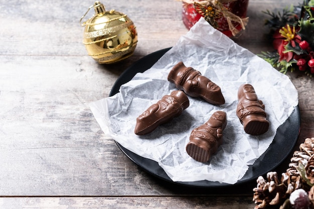 Foto grátis close-up de um alegre papai noel embrulhado em chocolate em uma mesa de madeira