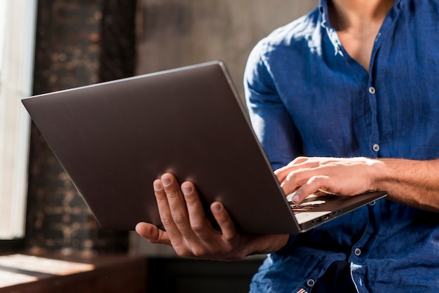 Foto grátis close-up, de, um, homem jovem, usando computador portátil, em, mão