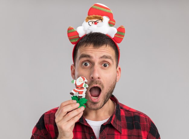 Close-up de um jovem impressionado com uma fita de Natal tocando o rosto com um boneco de neve, olhando para a câmera, isolada no fundo branco