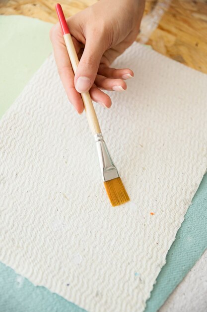 Close-up, de, um, mão mulher, segurando, pincel, sobre, branca, papel