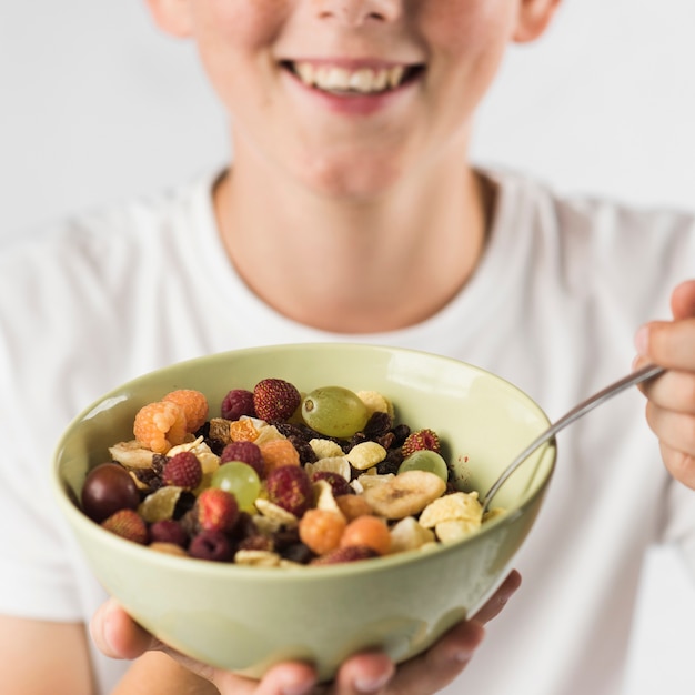 Foto grátis close-up, de, um, menino sorridente, mostrando, salada fruta, em, tigela cerâmica