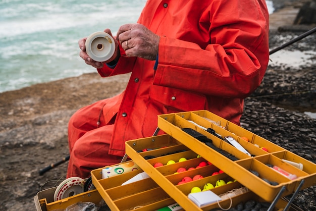 Close-up de um pescador colocando uma isca com a caixa de equipamentos de pesca. pesca e conceito de esporte.