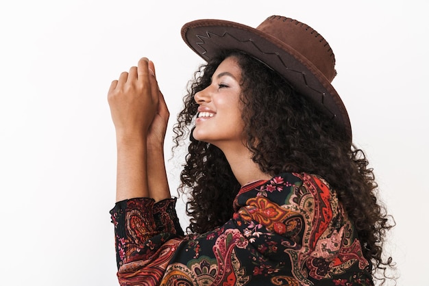 Close-up de uma bela jovem alegre usando chapéu de cowboy em pé, isolado sobre uma parede branca