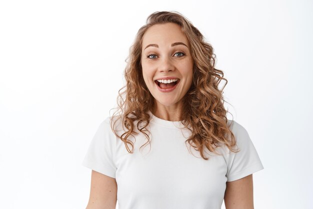 Close-up de uma loira animada sorrindo satisfeita olhando com alegria e gratidão em camiseta contra fundo branco Copiar espaço