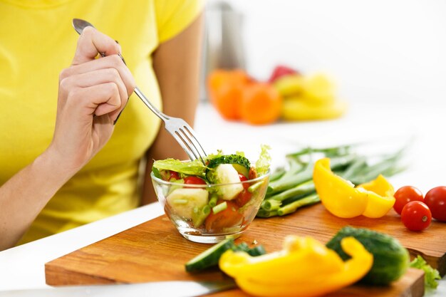 Close-up de uma mulher comendo salada na cozinha
