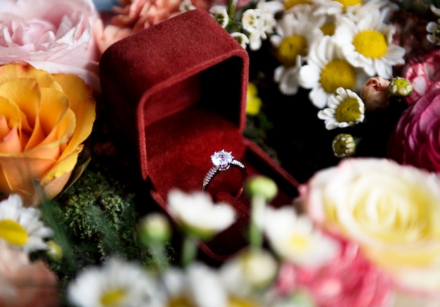 Close-up do anel de casamento na caixa vermelha com decoração de arranjo de flores