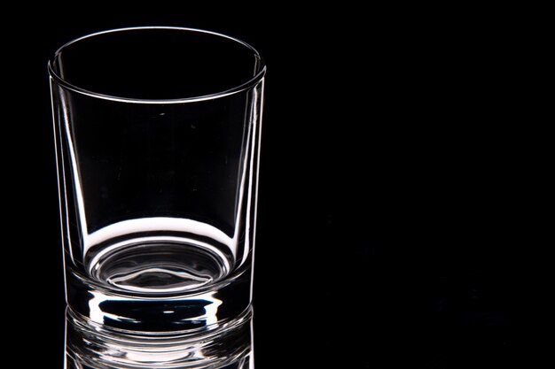 Close-up do copo de vidro vazio no lado direito em um fundo escuro com espaço livre