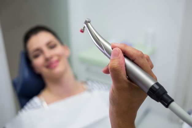 Close-up do dentista segurando uma odontologia, peça de mão dental enquanto examina uma mulher