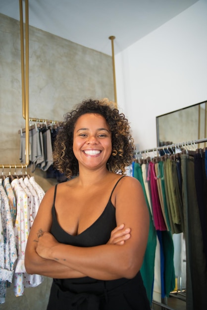 Foto grátis close-up do dono da loja em sua loja de roupas modernas. jovem mulher afro-americana em pé perto de cabides com camisas masculinas, calças e roupas íntimas. moda, inicialização de negócios de roupas e conceito de compras