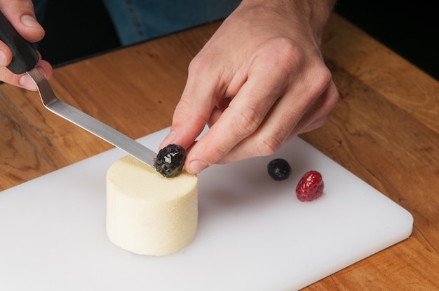 Foto grátis close up do homem colocando berry na paz de sorvete na mesa