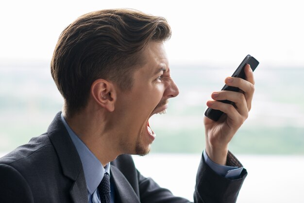 Close up do homem de negócios Shouting no Smartphone