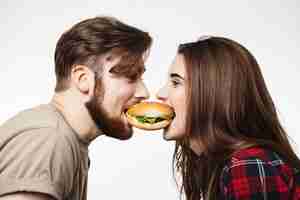 Foto grátis close up do homem e da mulher que comem um hamburguer junto.