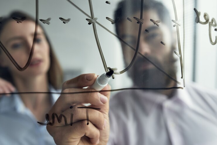 Foto grátis close-up do homem explicando análise de negócios para sua colega com um gráfico no quadro branco